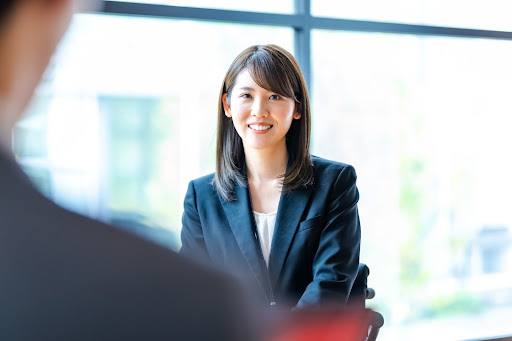 セミロングの20代女性社員が笑顔で座っている様子