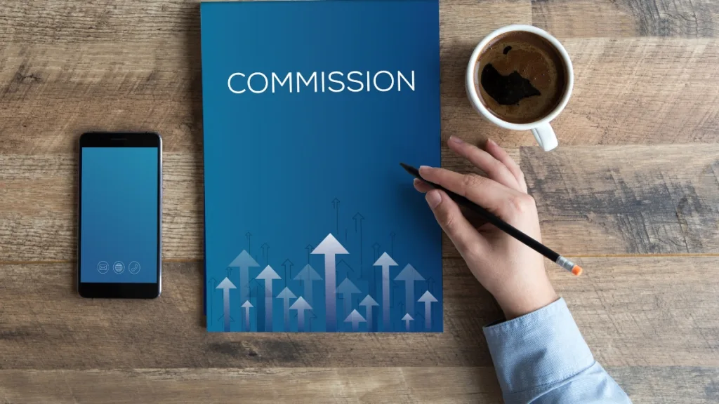 机の上COMMISSIONの文字が青い冊子がありコーヒーが置いてある。