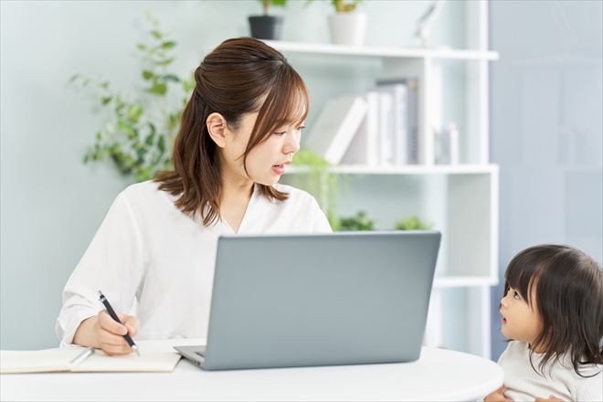 リモートワークをする女性の横に女児