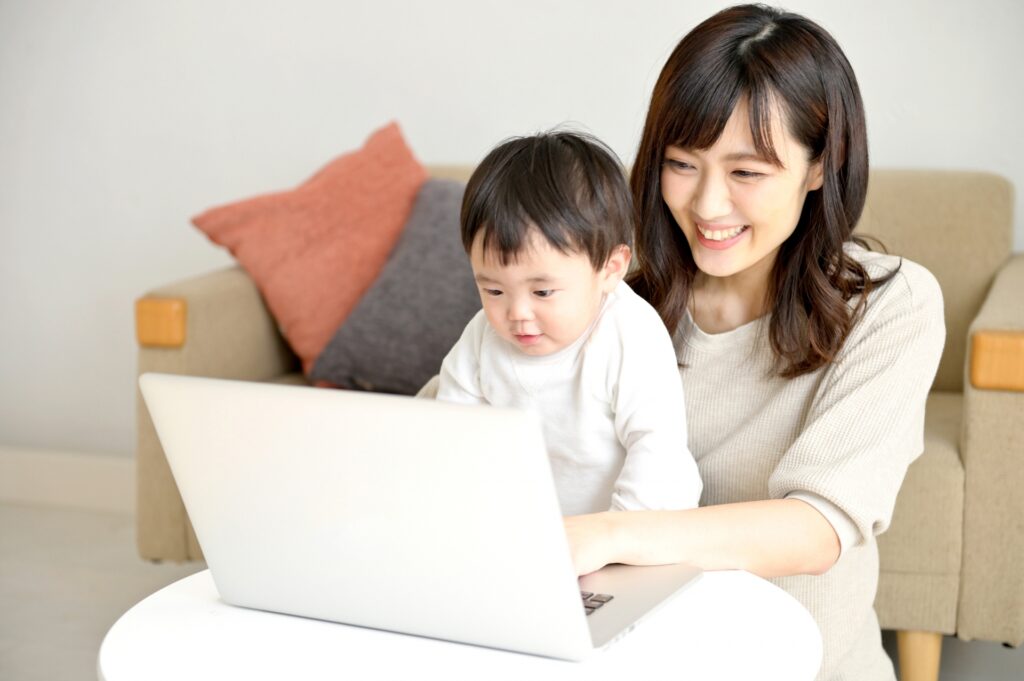 パソコンを操作する母親と赤ちゃん
