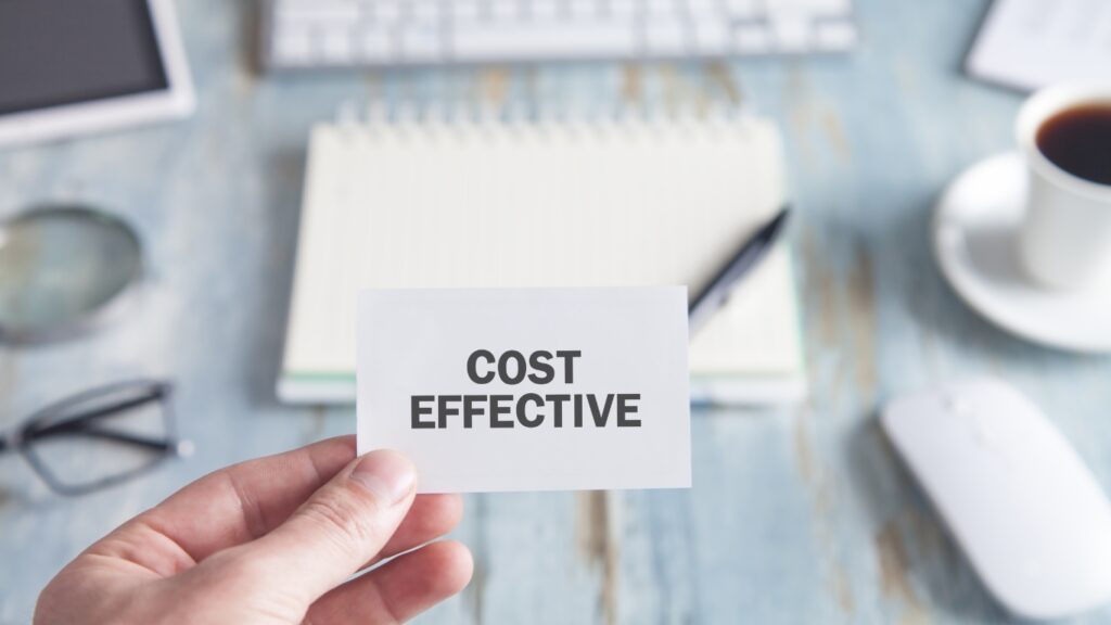 COST EFFECTIVEの文字を書いた紙を持つ人