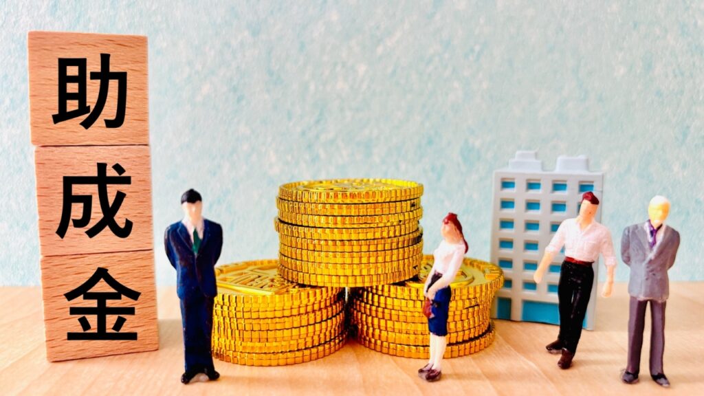 木のブロックに助成金の文字、コインとフィギュア