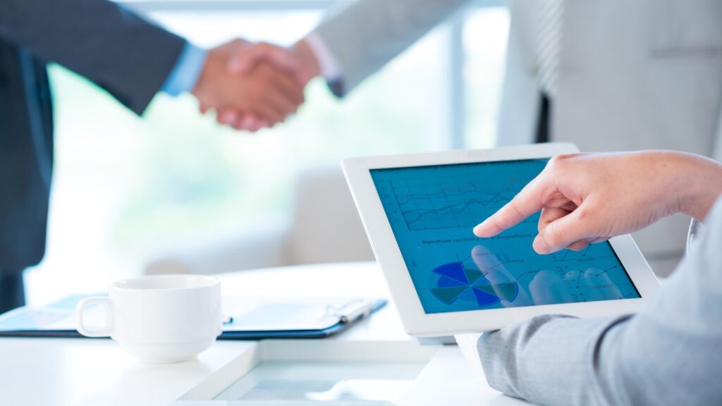 握手するビジネスパーソンとタブレットを操作する手