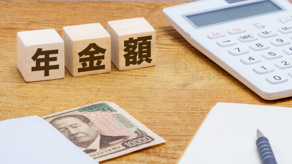 年金額の木のブロックと一万円札と電卓