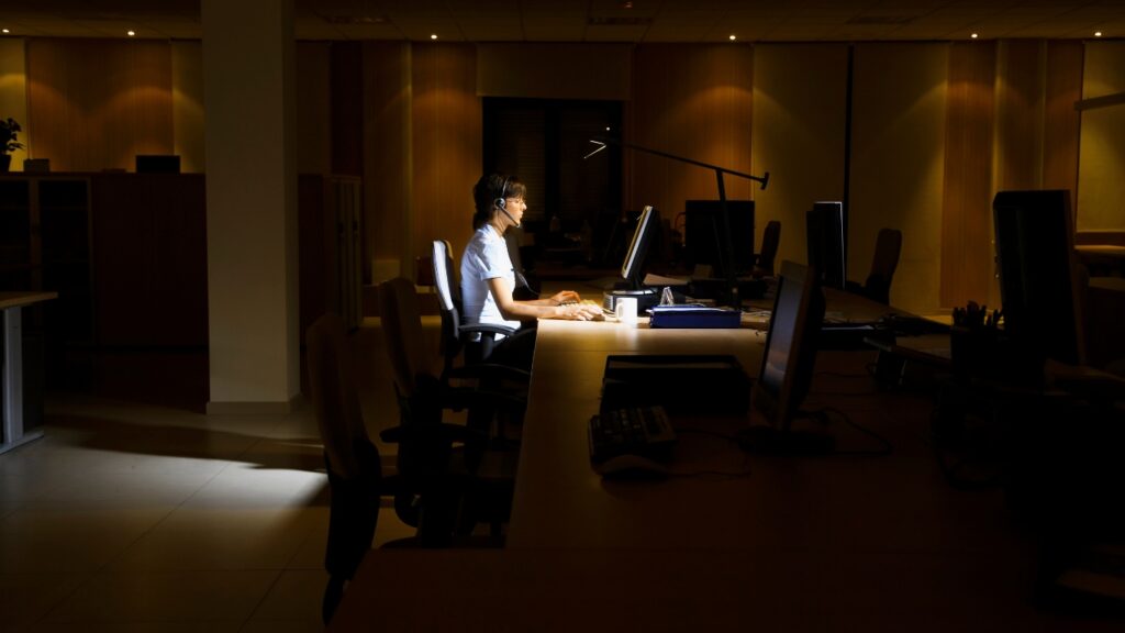 暗いオフィスでノートパソコンを操作する女性