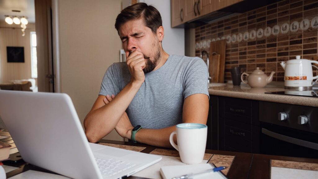 あくびをしながら仕事をする男性